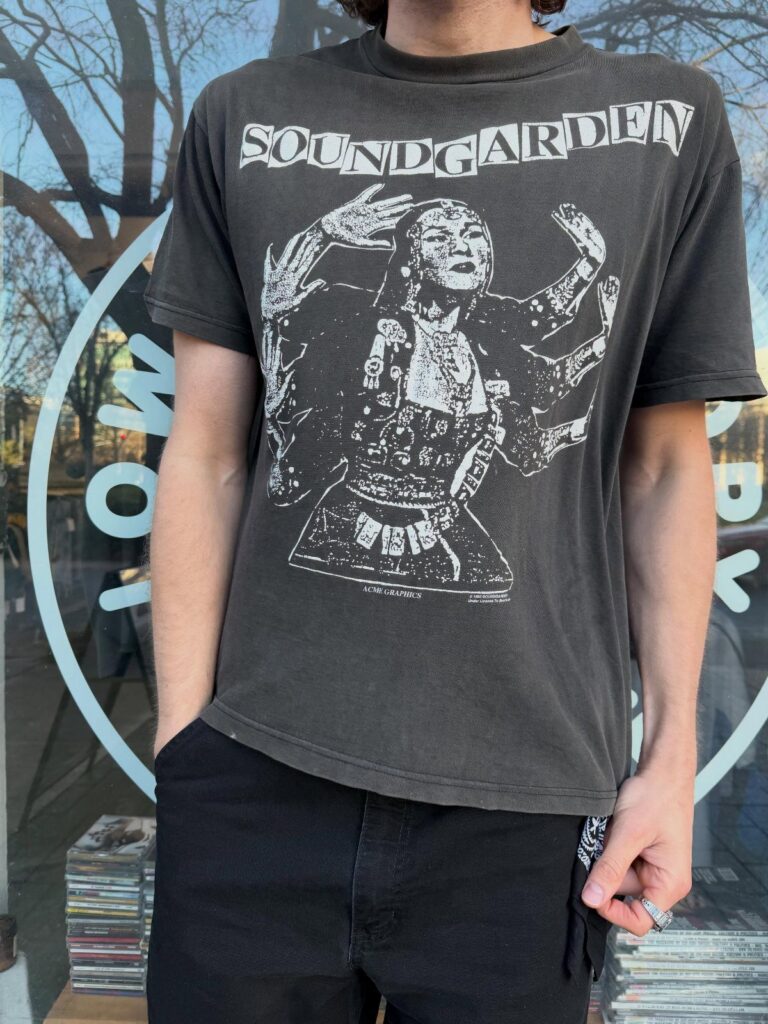 A person wearing a faded black Soundgarden graphic t-shirt and black pants.