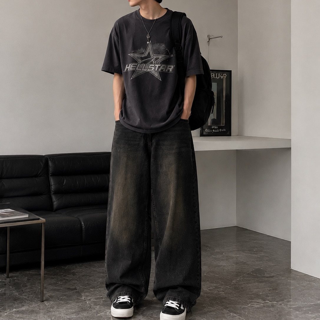 Man wearing a black graphic t-shirt and oversized dark grey baggy trousers with sneakers.