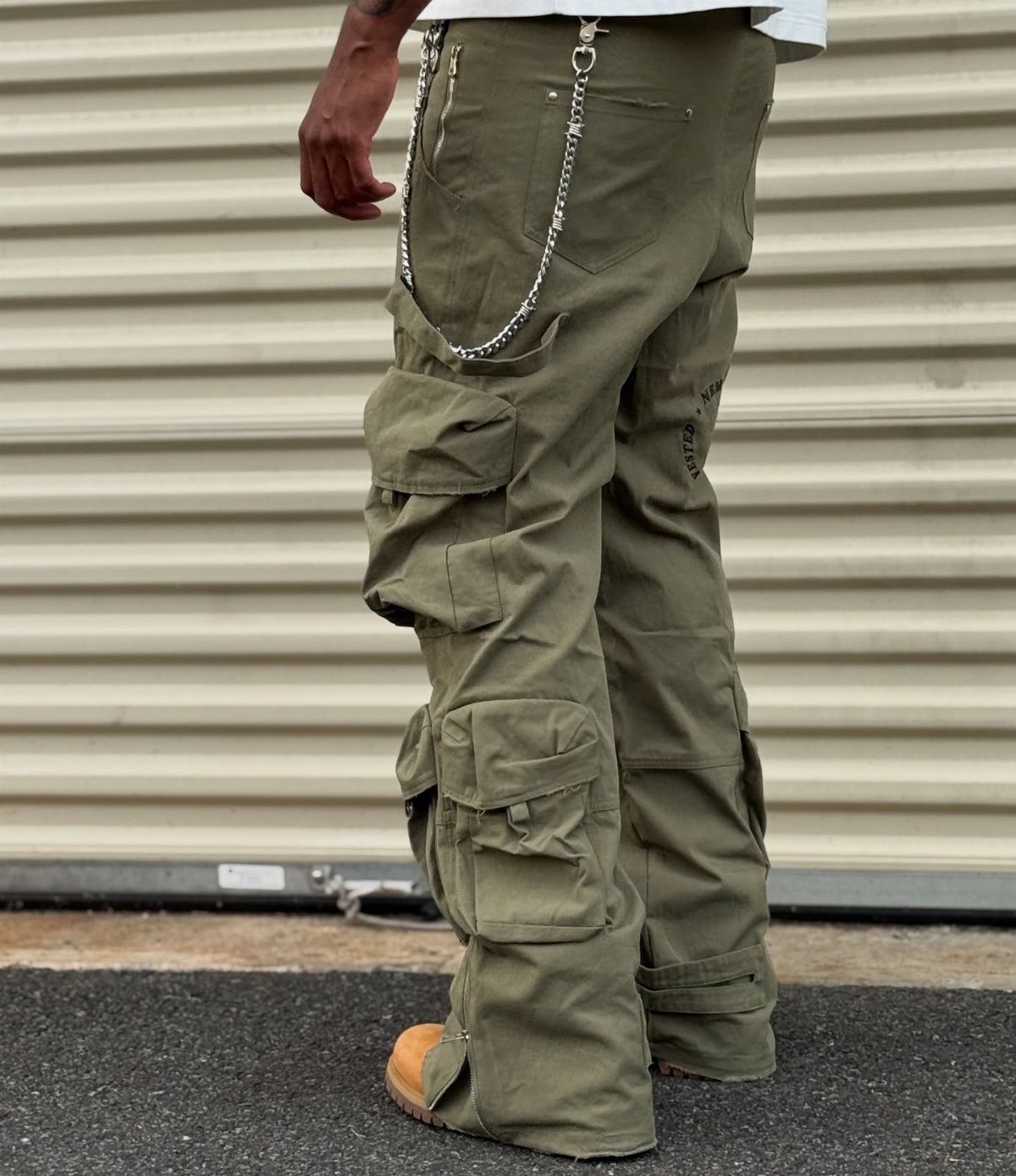 Person wearing olive green cargo pants with large pockets and a silver waist chain.