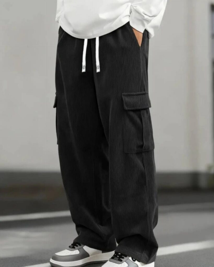 Person wearing wide black corduroy cargo pants with white drawstring and white sneakers.