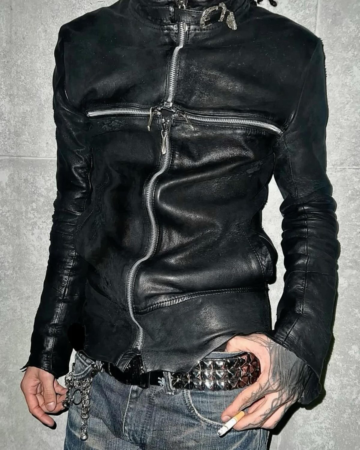 Person wearing a black leather jacket with silver zippers and a studded belt.