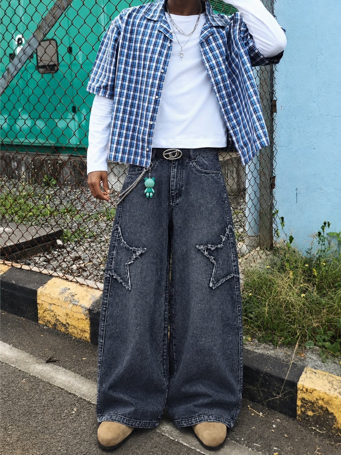Person wearing oversized baggy dark denim jeans with large star patches and a blue plaid shirt.
