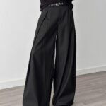 Person wearing black high-waisted wide-leg pleated trousers and a black long-sleeved shirt.