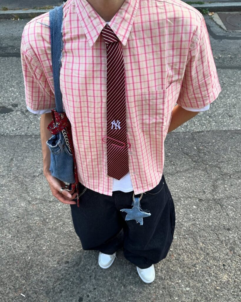 Person wearing a pink checkered shirt, striped tie, baggy black pants, and white shoes.